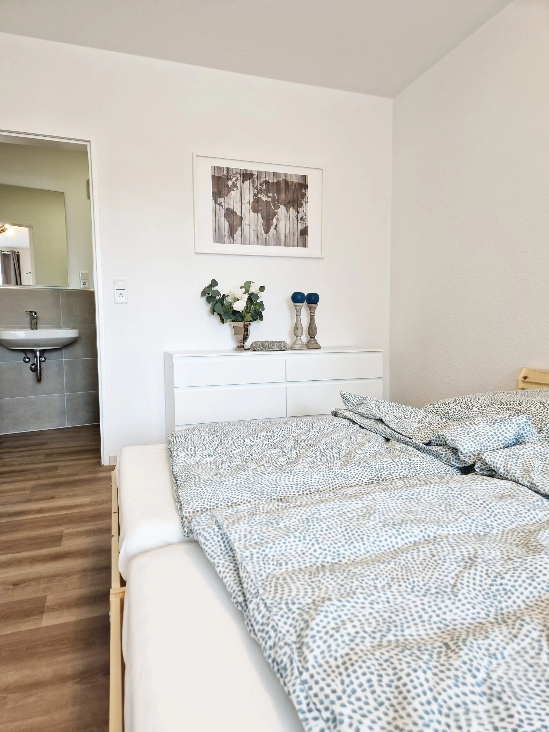 Betten im Doppelzimmer mit weißer Kommode und gerahmtem Bild an der Wand