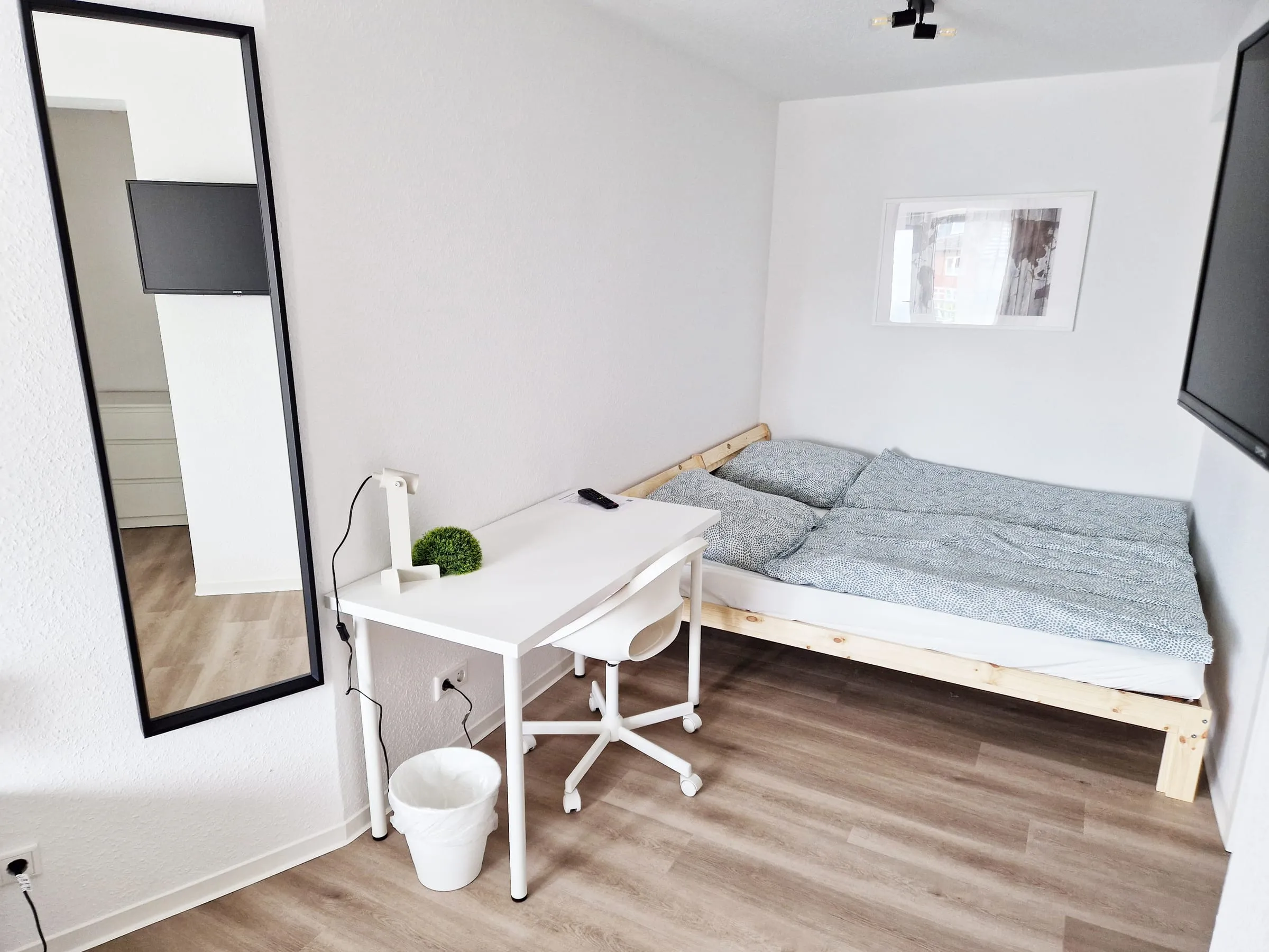 Blick ins Dreibettzimmer mit Standspiegel, Schreibtisch und Betten an der Wand