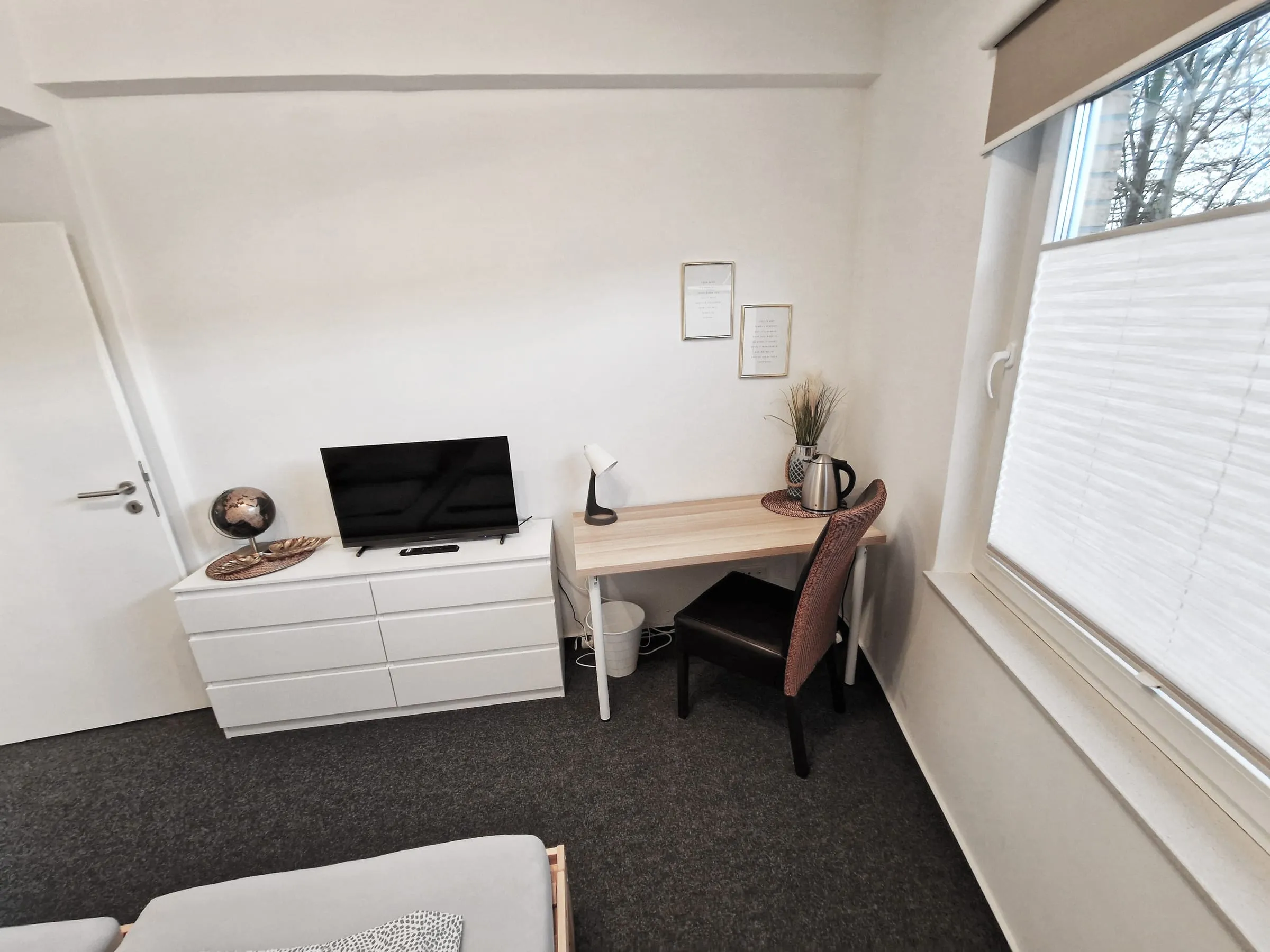 Fernseher auf der Kommode und Schreibtisch mit Stuhl im Premiumzimmer