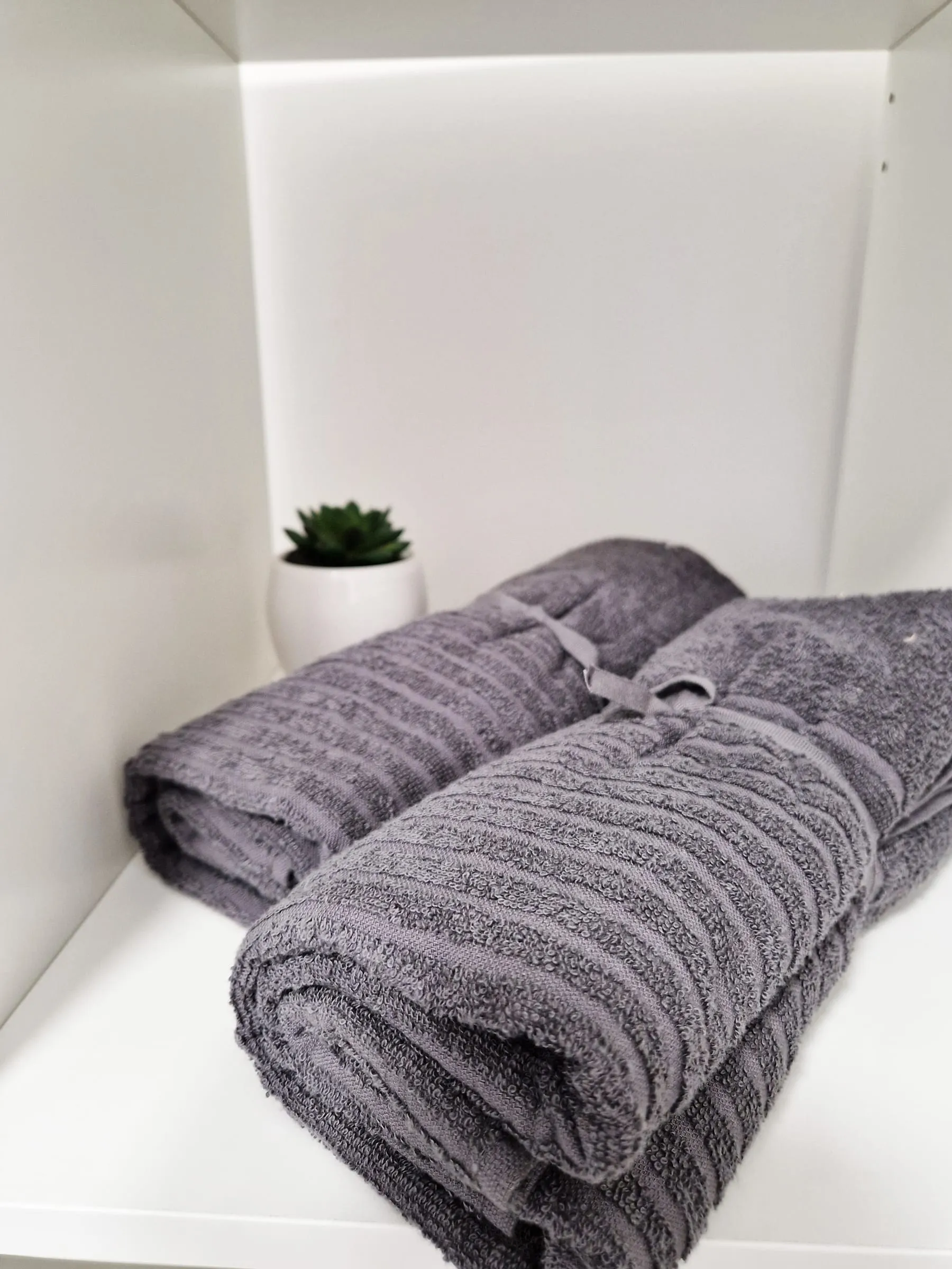 Frische Handtücher, zusammengerollt auf dem Bett im Doppelzimmer